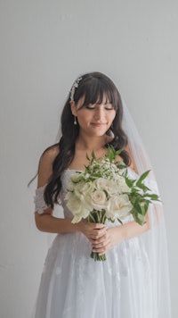 a bride in a white wedding dress holding a bouquet of flowers